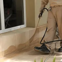 General pest control technician spraying exterior perimeter around a home in San Antonio, TX