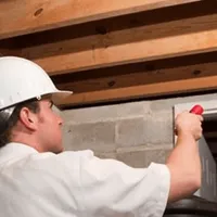 Termite inspection technician checking a basement wall and framing for termite activity in San Antonio, TX